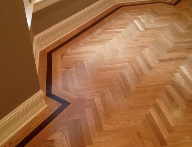 A wooden floor with a herringbone pattern and a black border