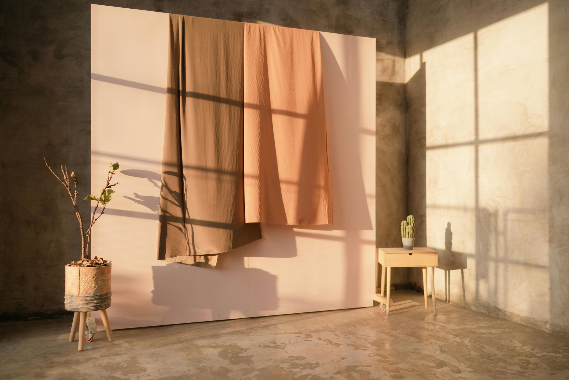 A room with a concrete floor , a window , a table and a plant.