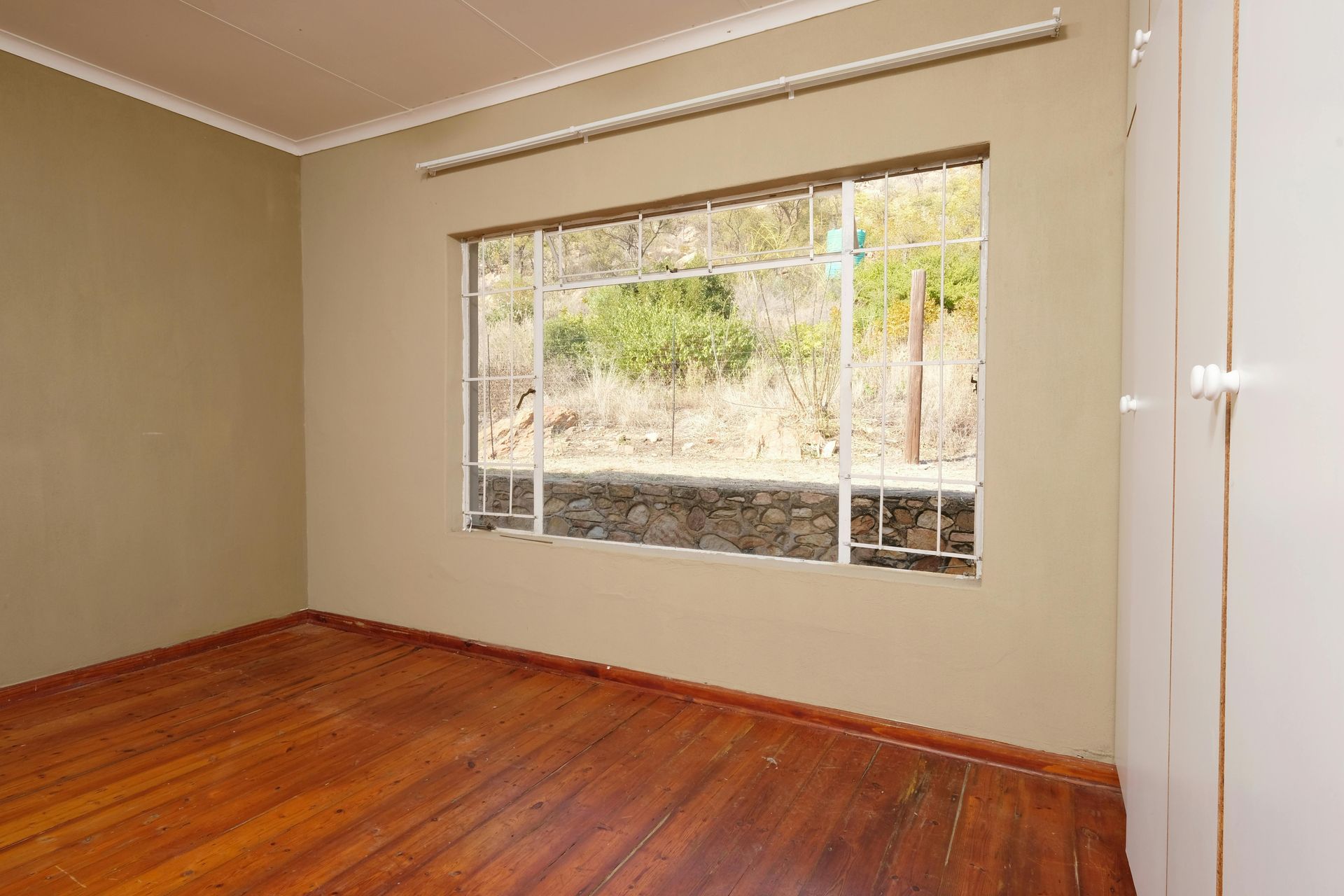 An empty room with hardwood floors and a large window.