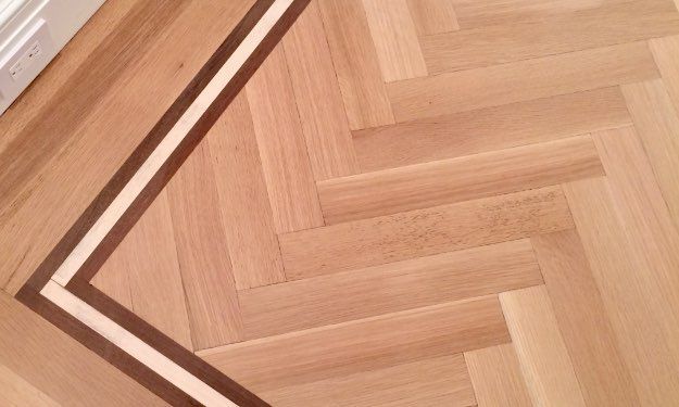 A close up of a wooden floor with a herringbone pattern.