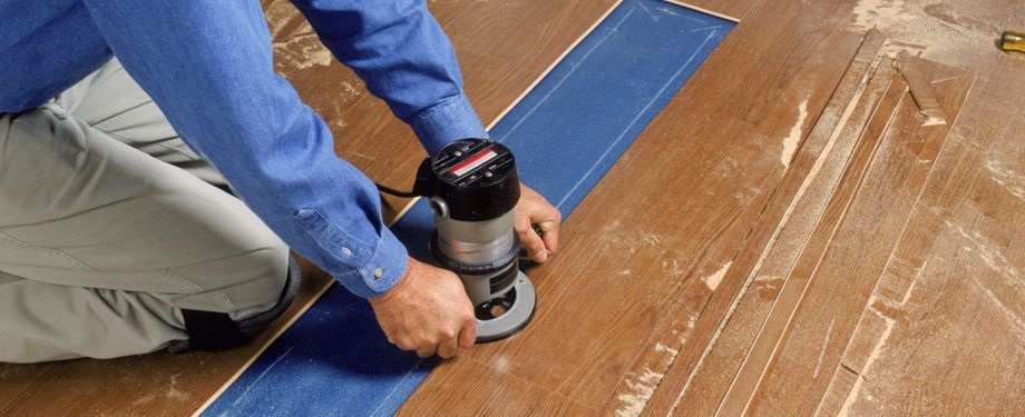 A man is using a router to cut a piece of wood.