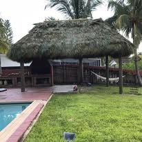 Thatched roof structure over a patio, with a pool and lawn.