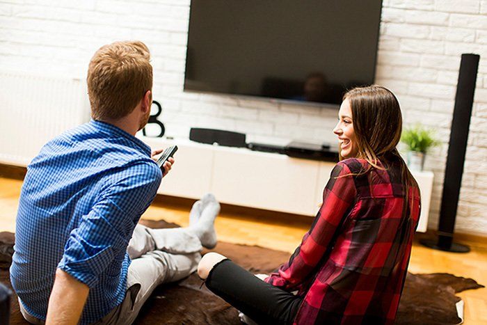 Man and woman watching tv on their home theater