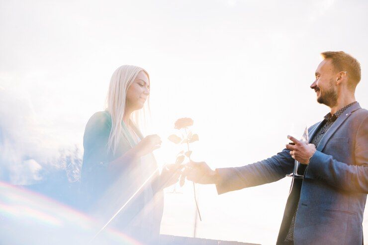 A man is giving a woman a rose and a glass of champagne.