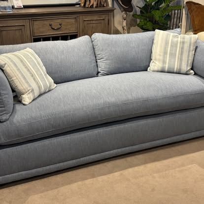 Blue upholstered sofa with striped throw pillows in a showroom setting.