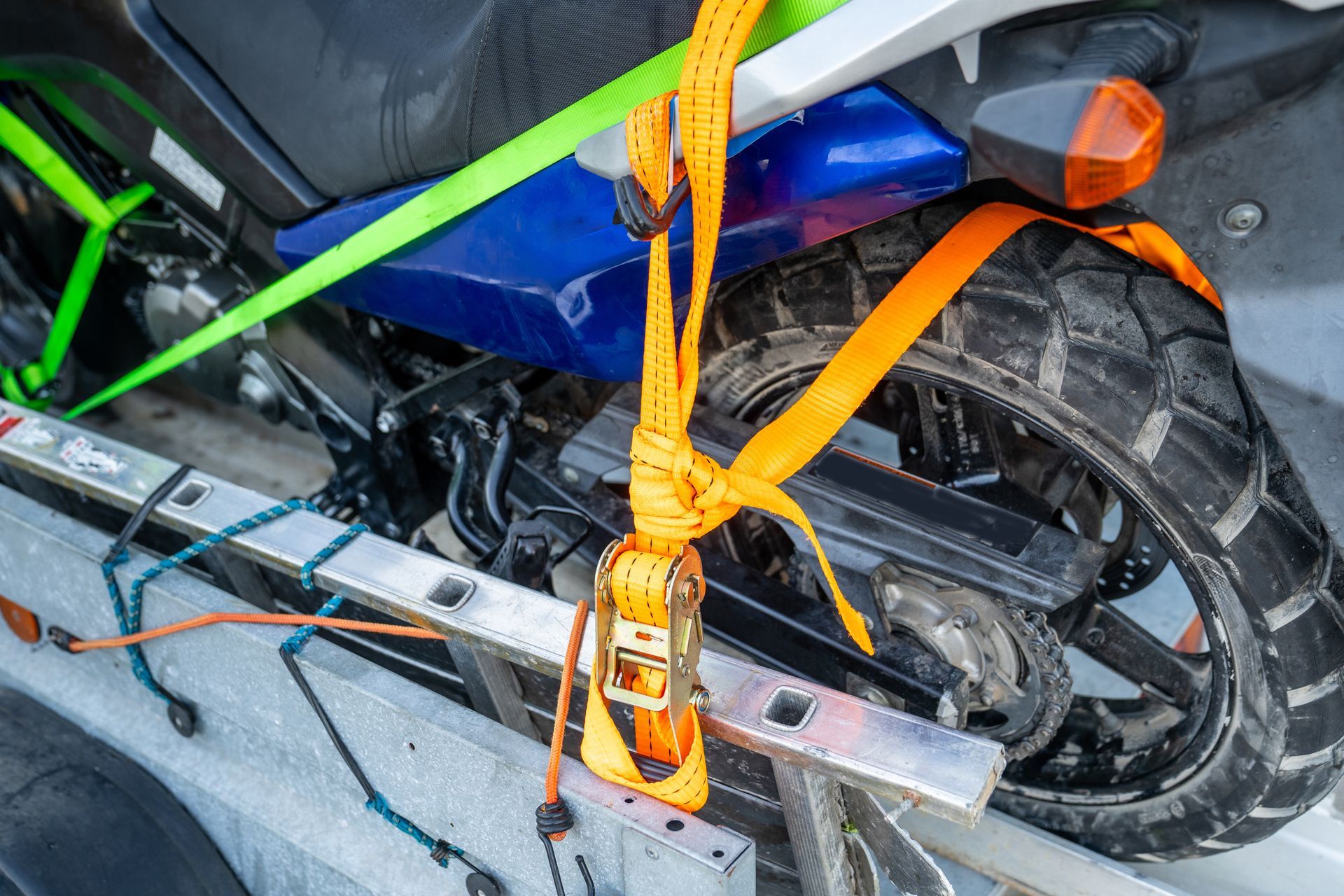 Motorcycle secured in a trailer with orange and green straps.