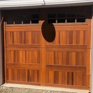 A wooden garage door with a hole in it.