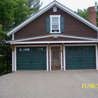 A brown house with green garage doors and a window.