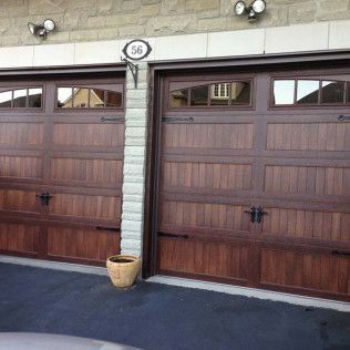 A pair of wooden garage doors with a potted plant in front of them.