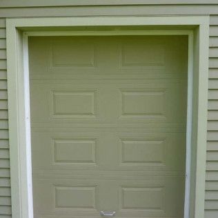 A green garage door is on the side of a house.