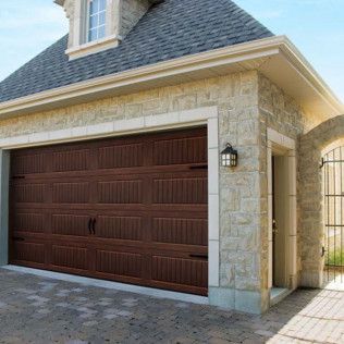 A large wooden garage door is on the side of a house.