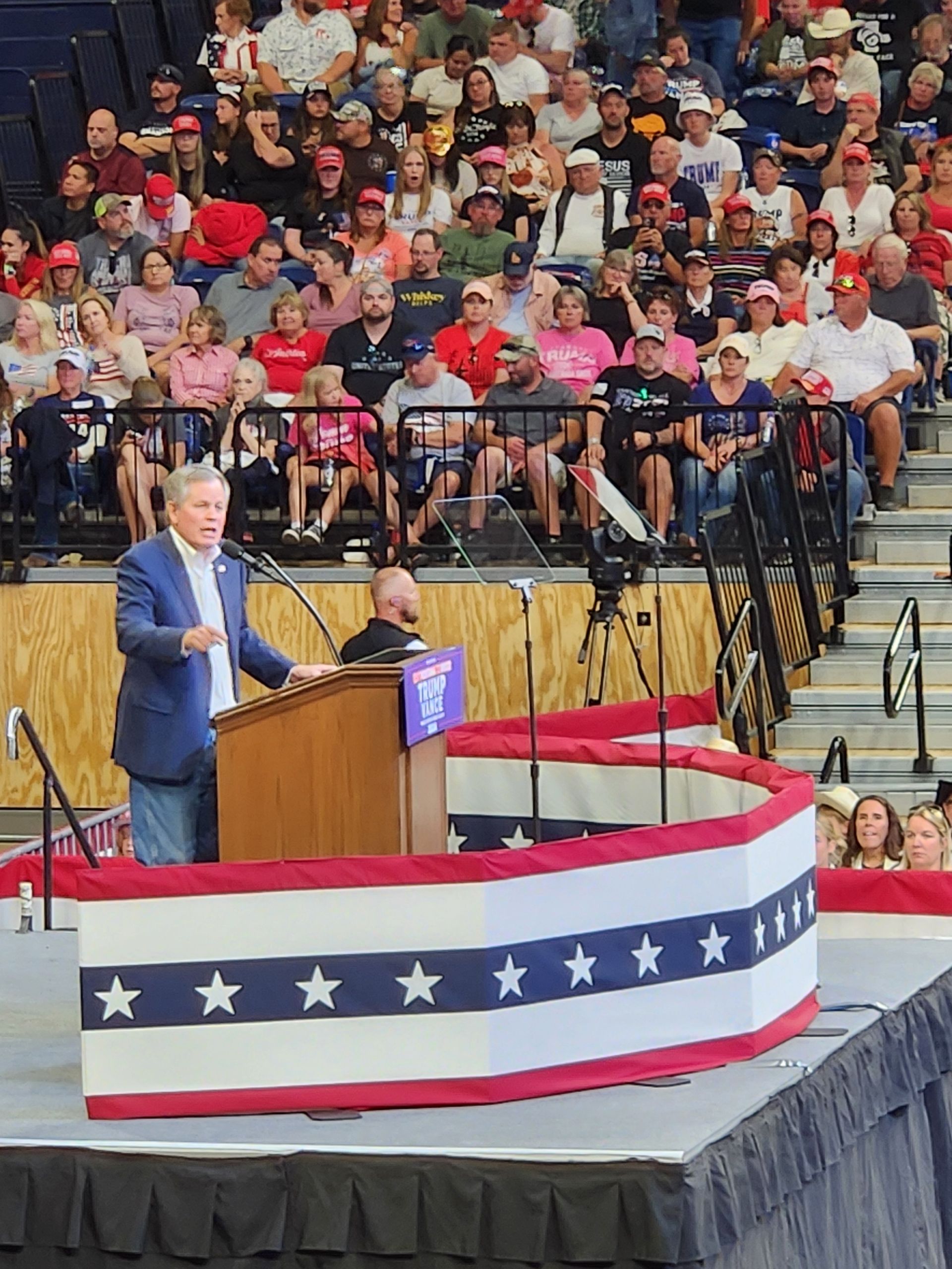 A man stands at a podium in front of a crowd of people