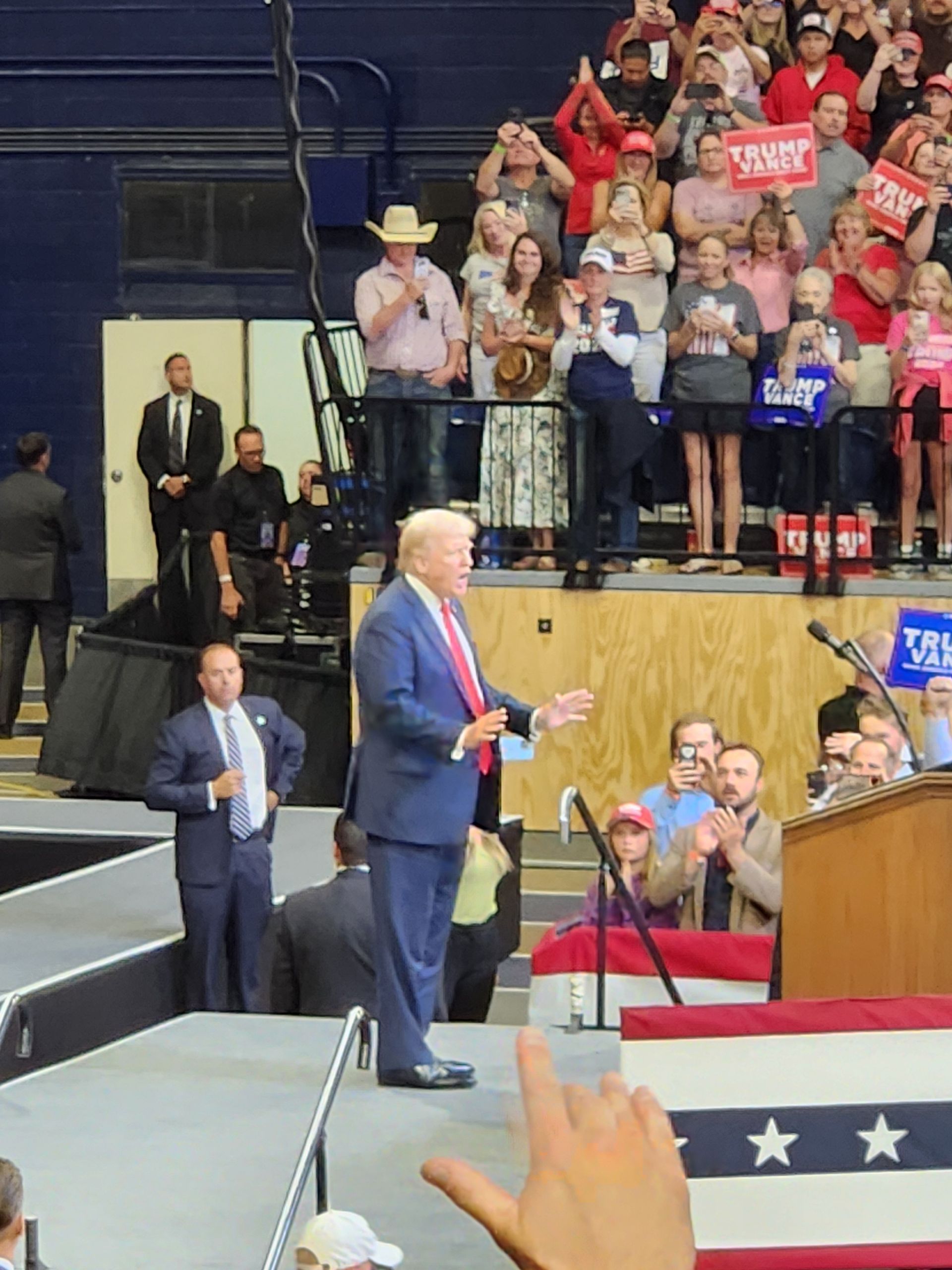 A man in a suit and tie is giving a speech in front of a crowd