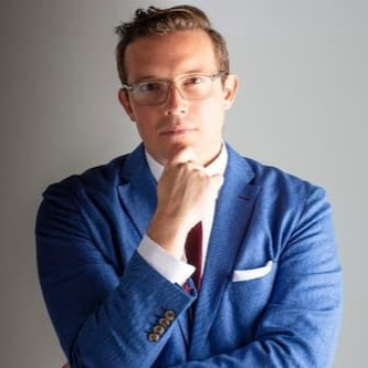 A man stands at a podium with microphones in front of American flags