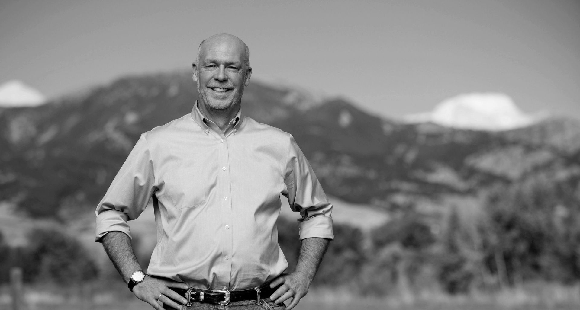 A man is standing in a field with his hands on his hips.