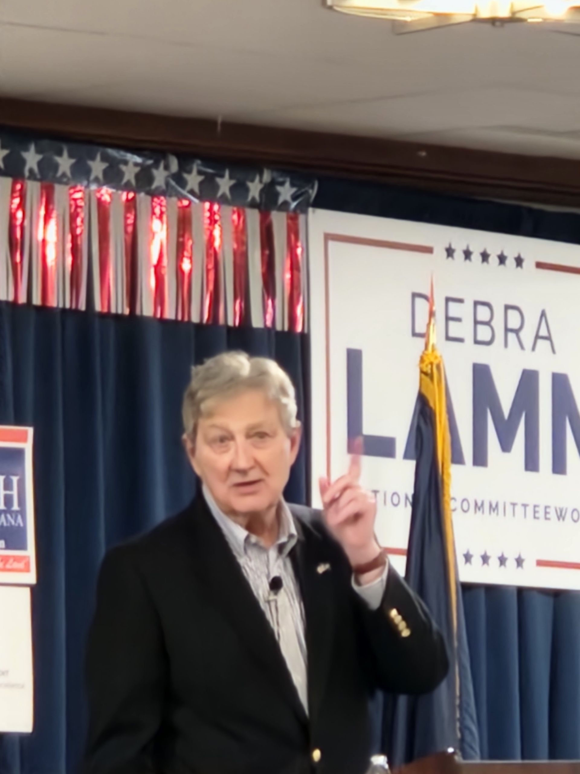 A man giving a speech in front of a sign that says debra lamm