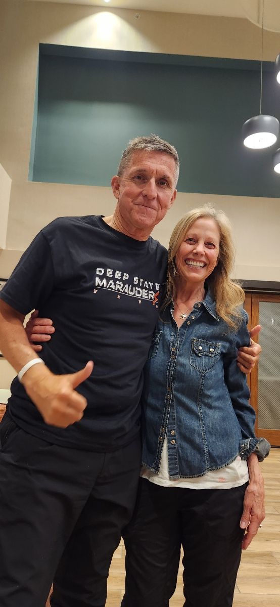 A man and a woman are posing for a picture and the man is giving a thumbs up.