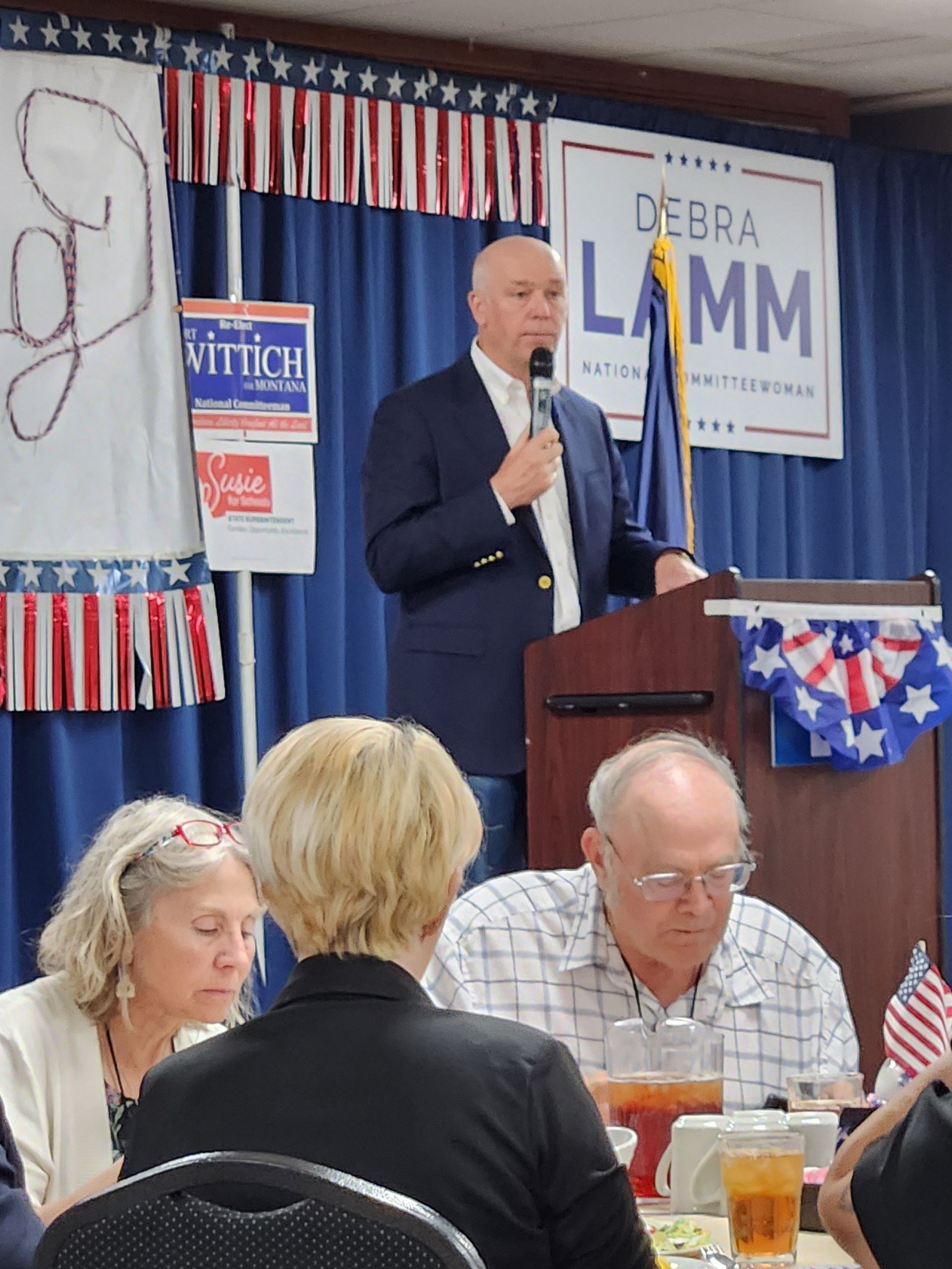 A man stands at a podium with a sign that says debra lamm