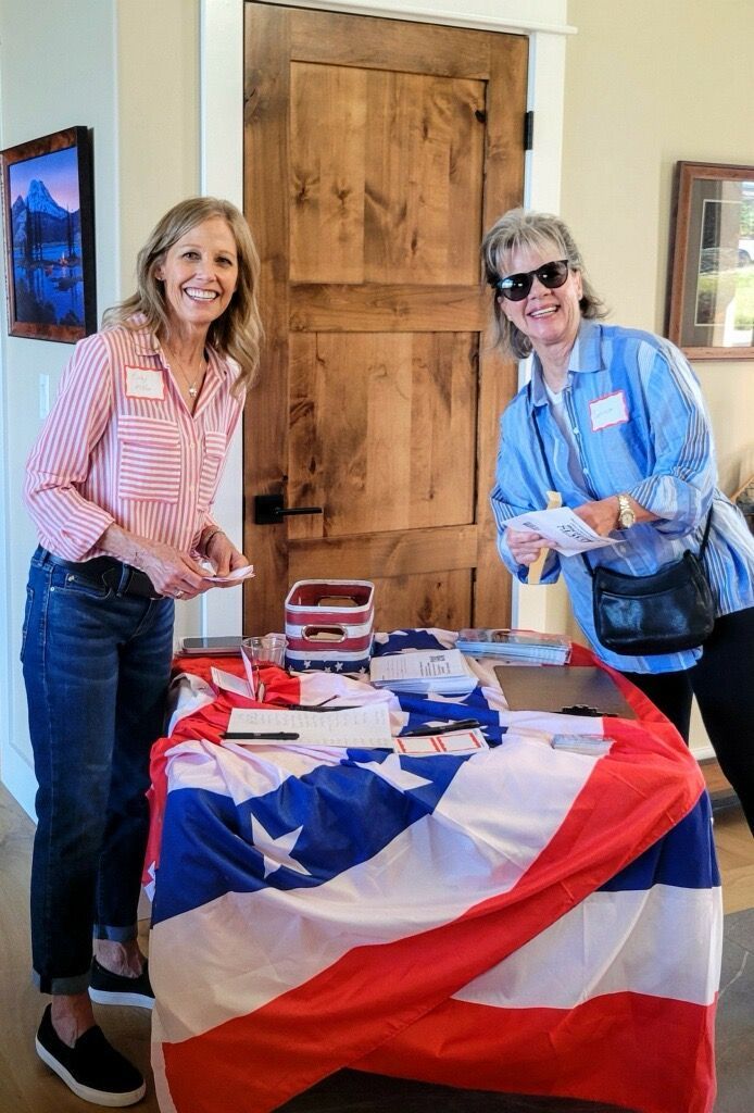 Two women are standing next to a table with an american flag on it.