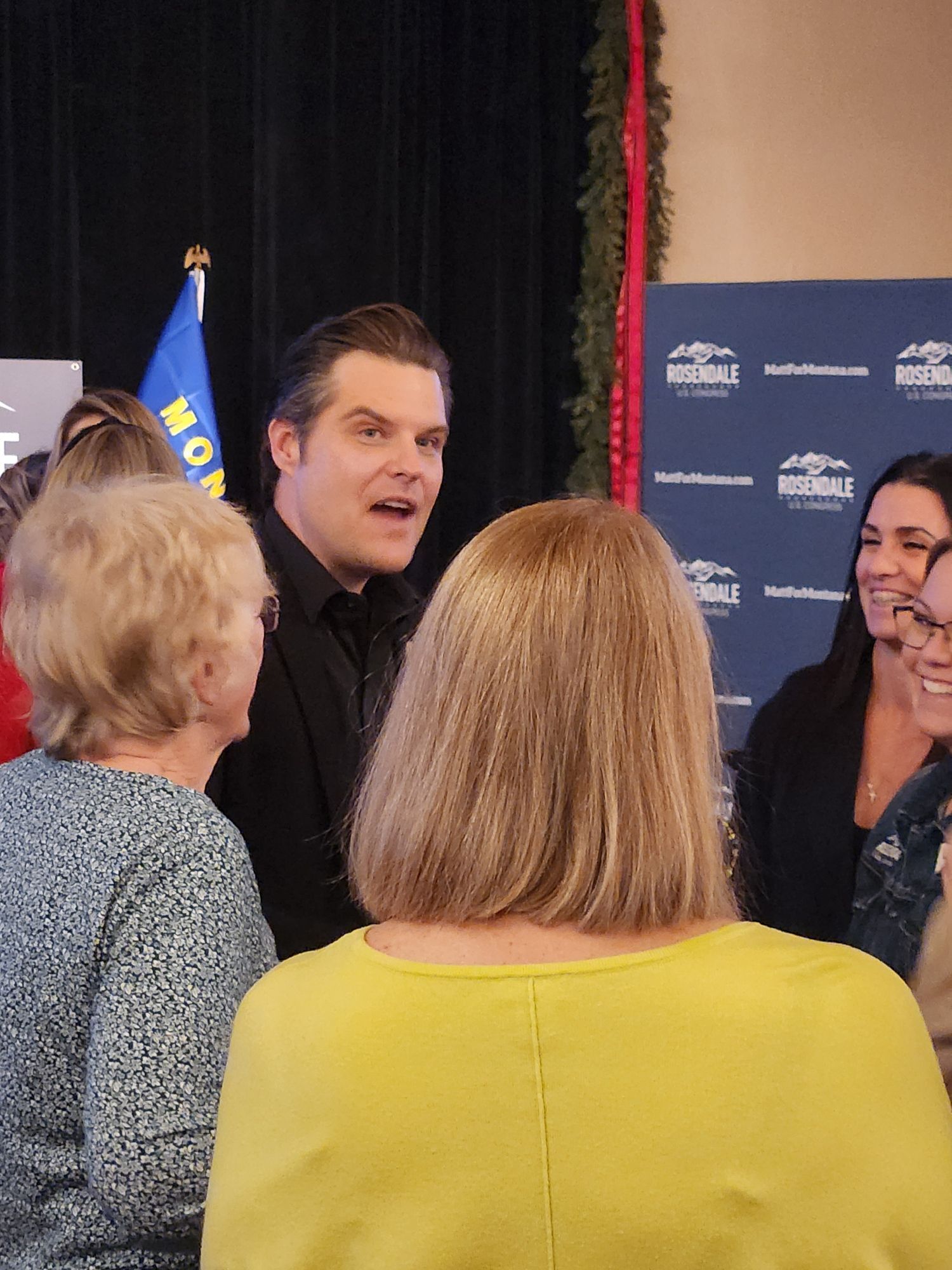 A group of people are standing around talking to each other.