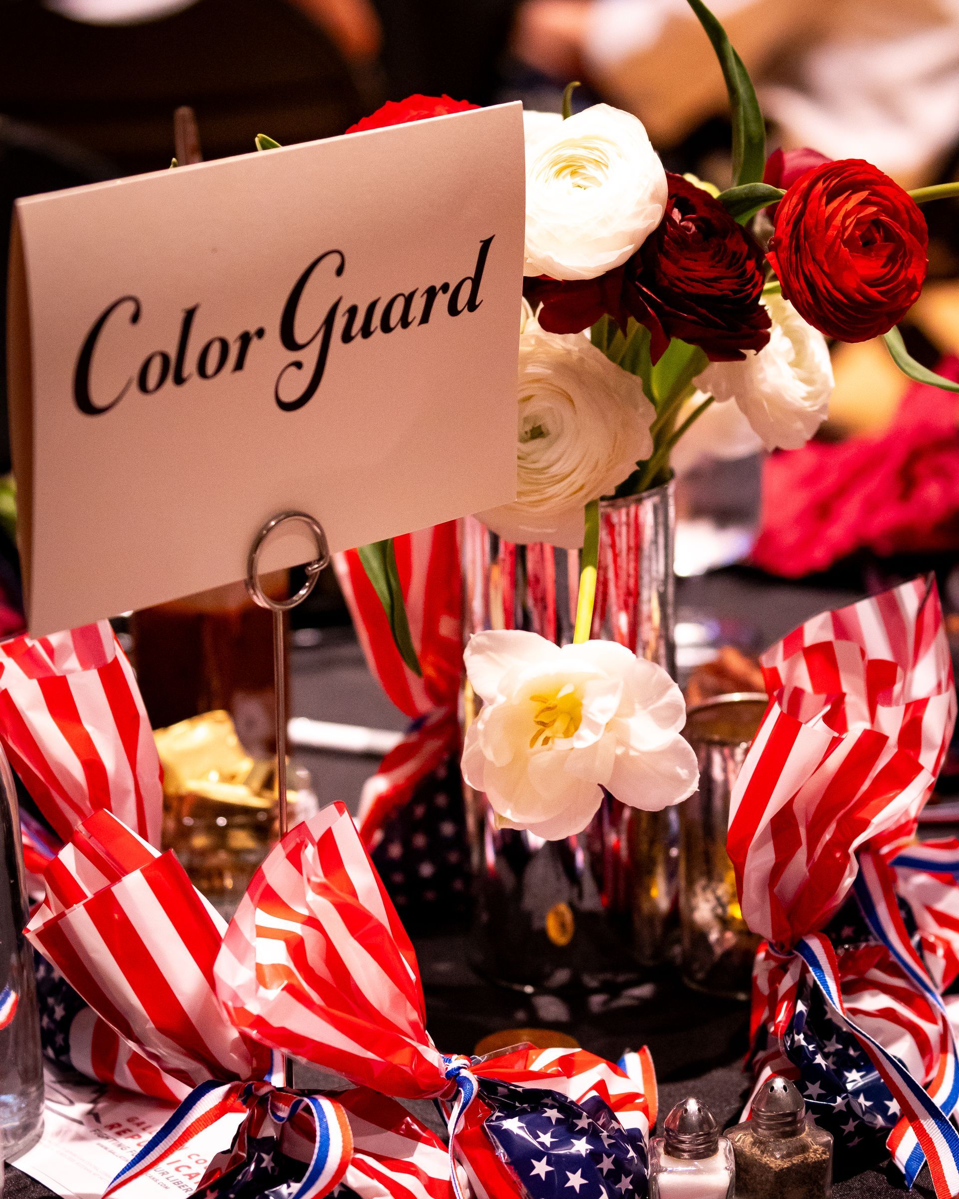 A table with flowers and a sign that says color guard