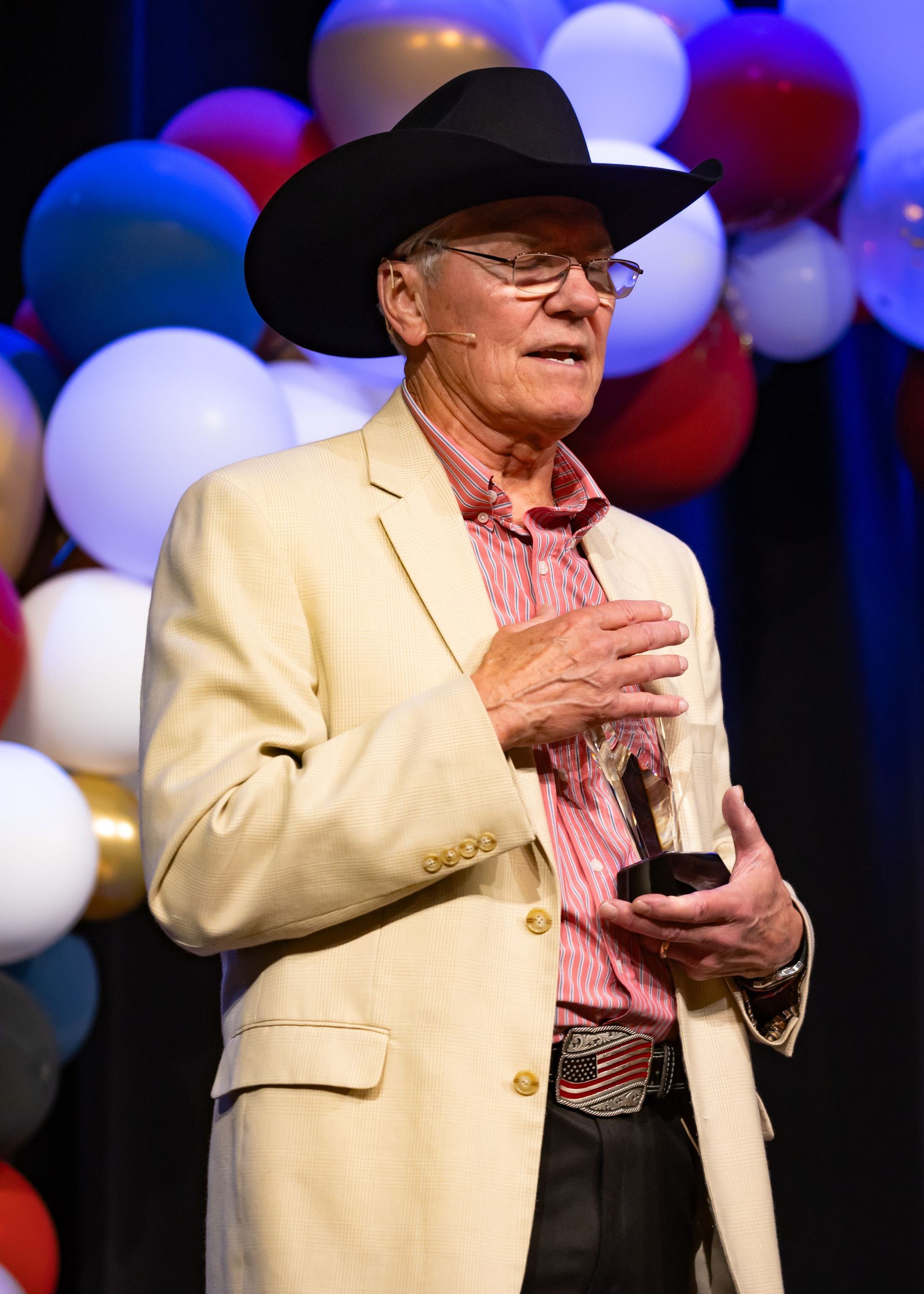 A man in a cowboy hat is standing in front of balloons