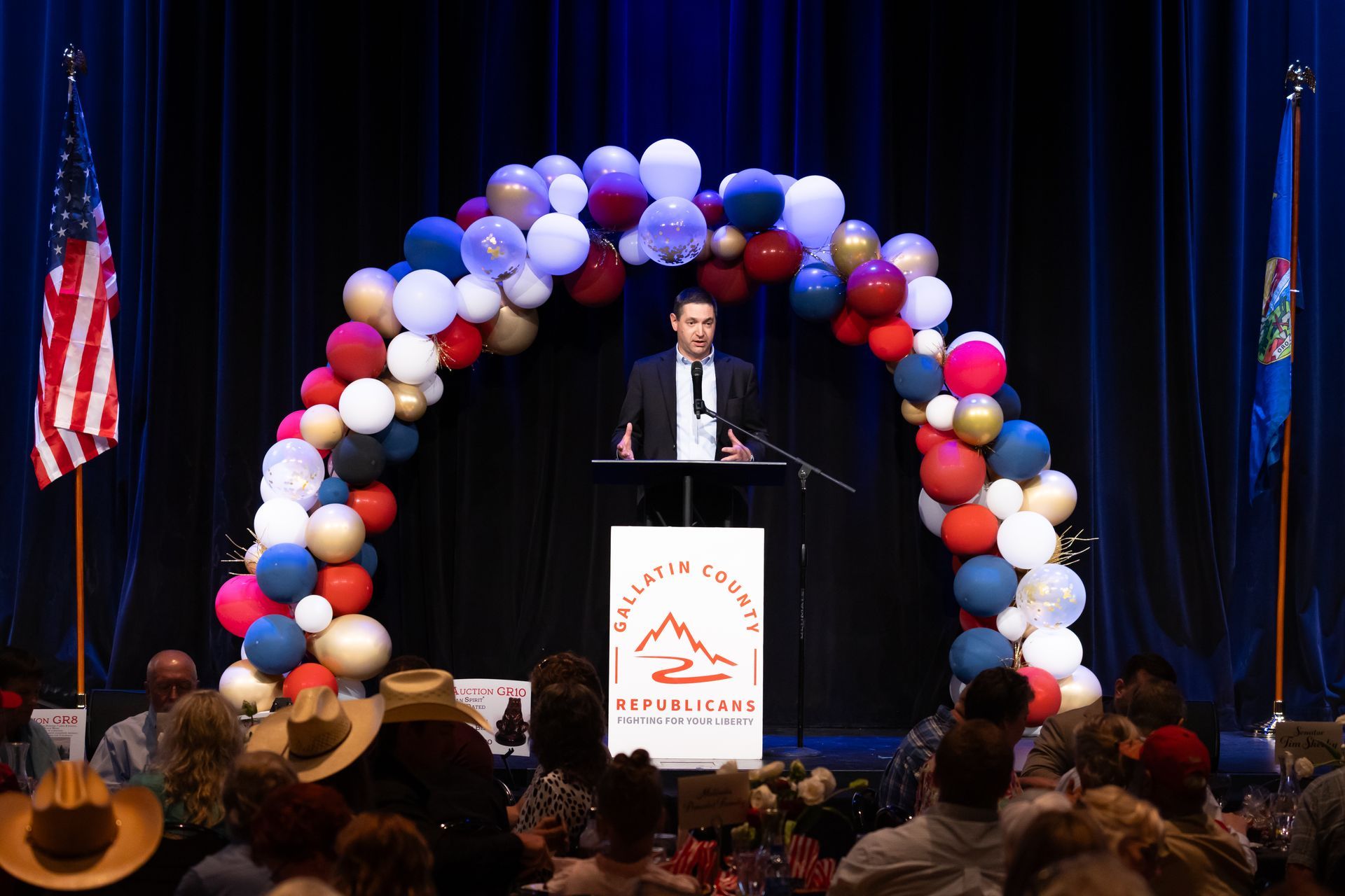 A man is standing at a podium in front of a crowd of people.