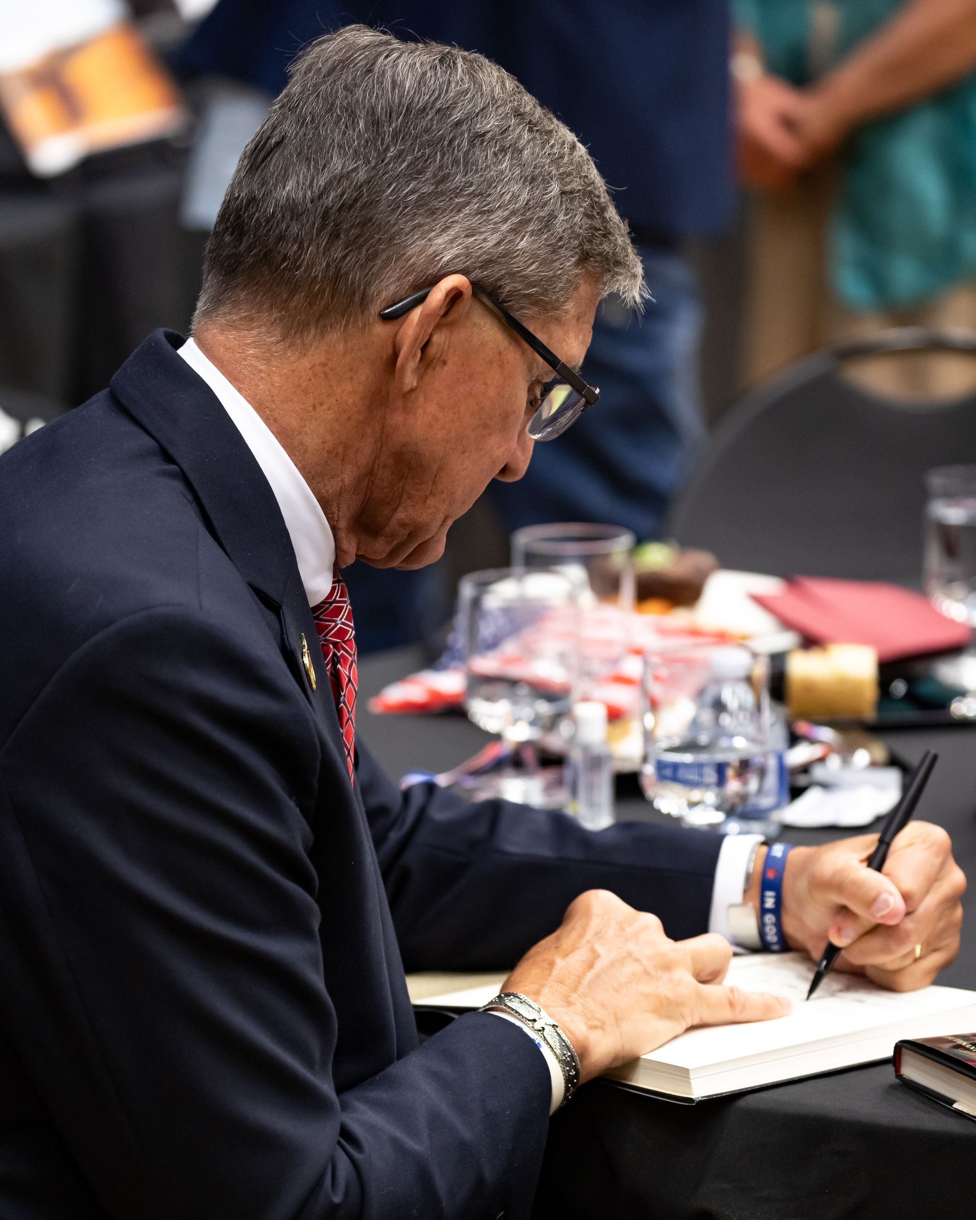 A man in a suit and tie is writing in a notebook