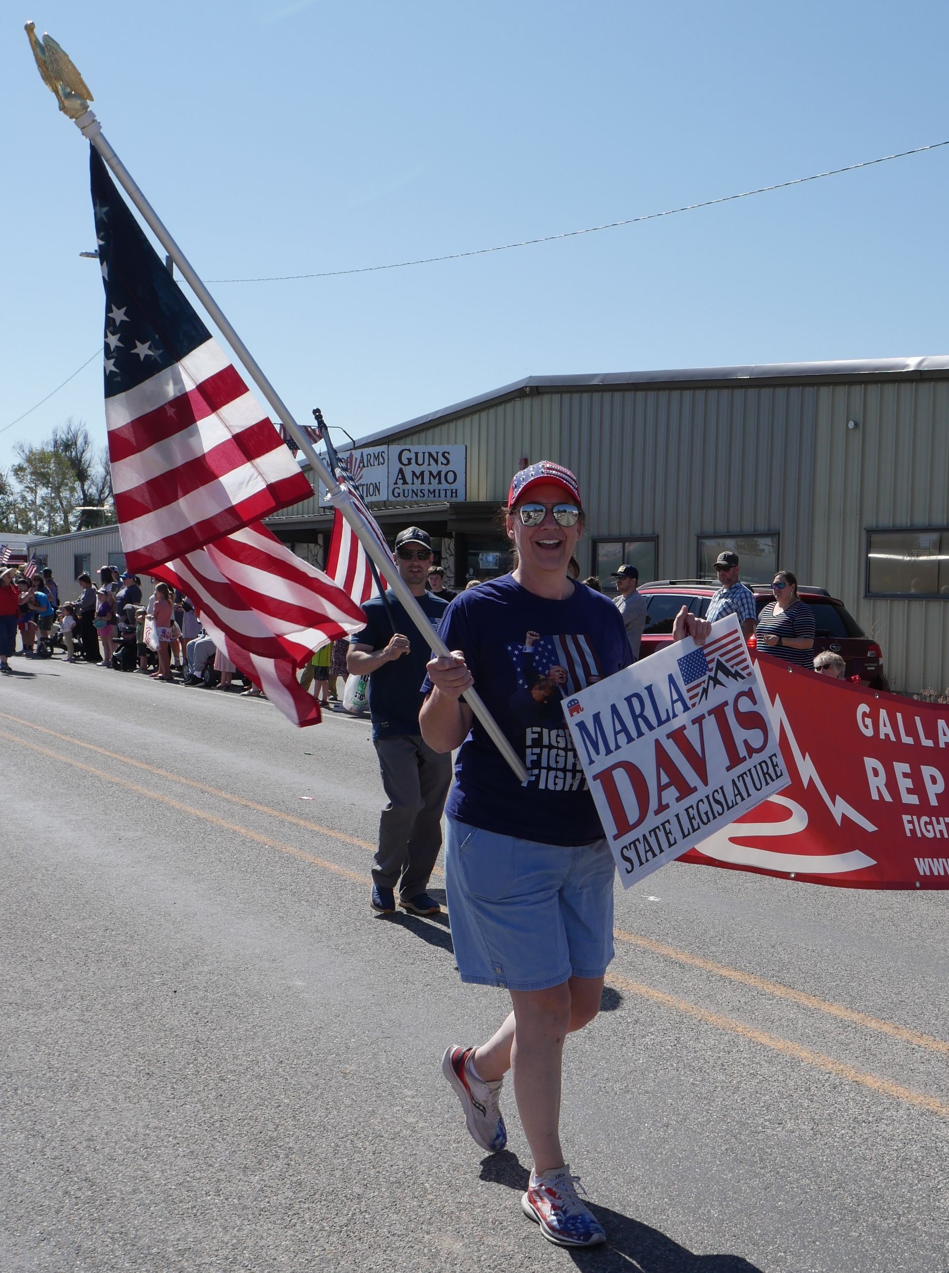 A woman is holding an american flag and a sign that says marlon davis