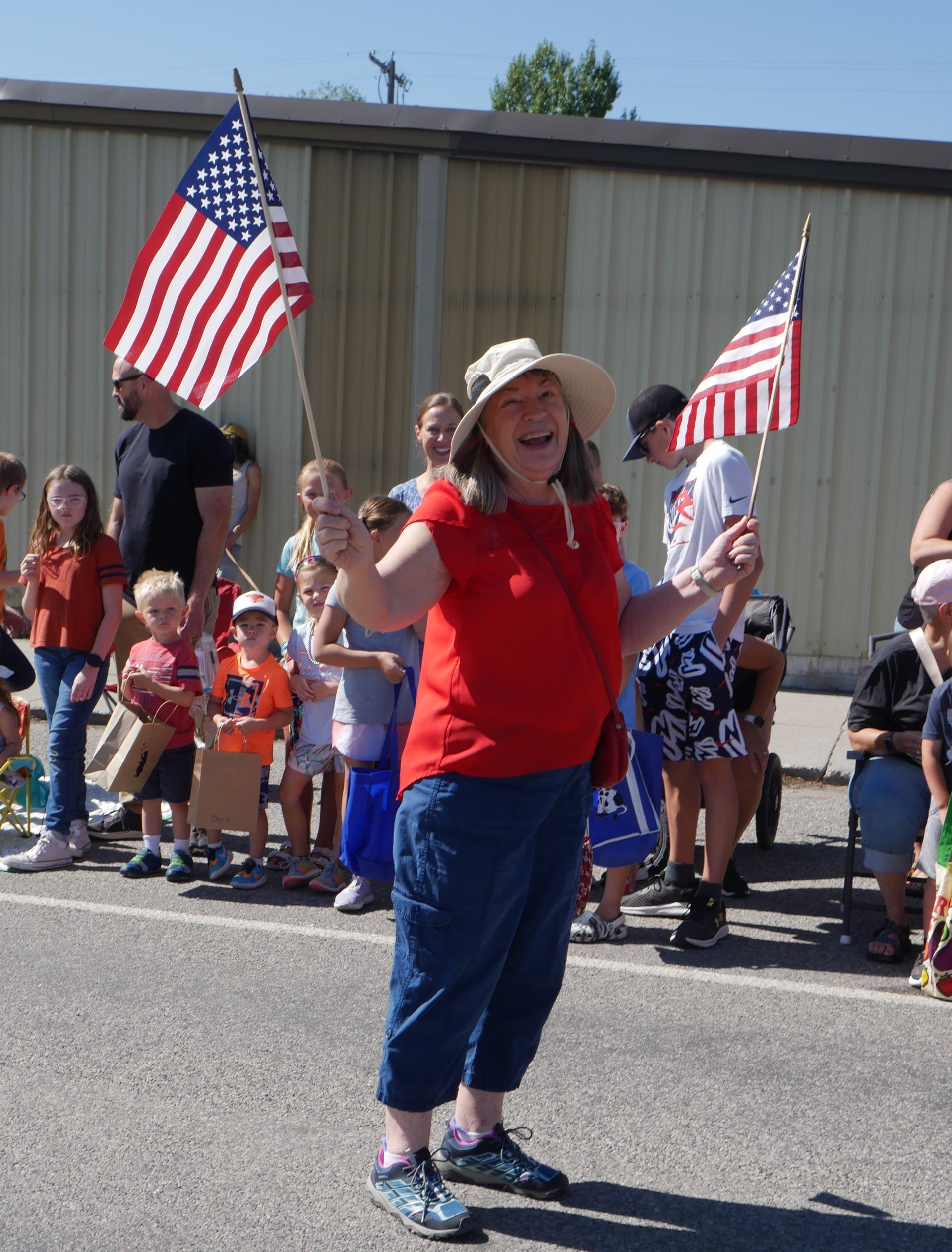 A woman in a red shirt is holding an american flag