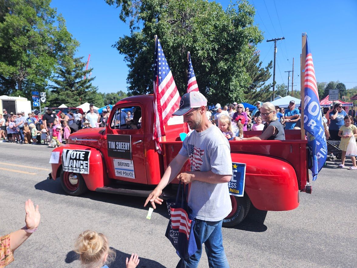 A man stands in front of a red truck in a parade.