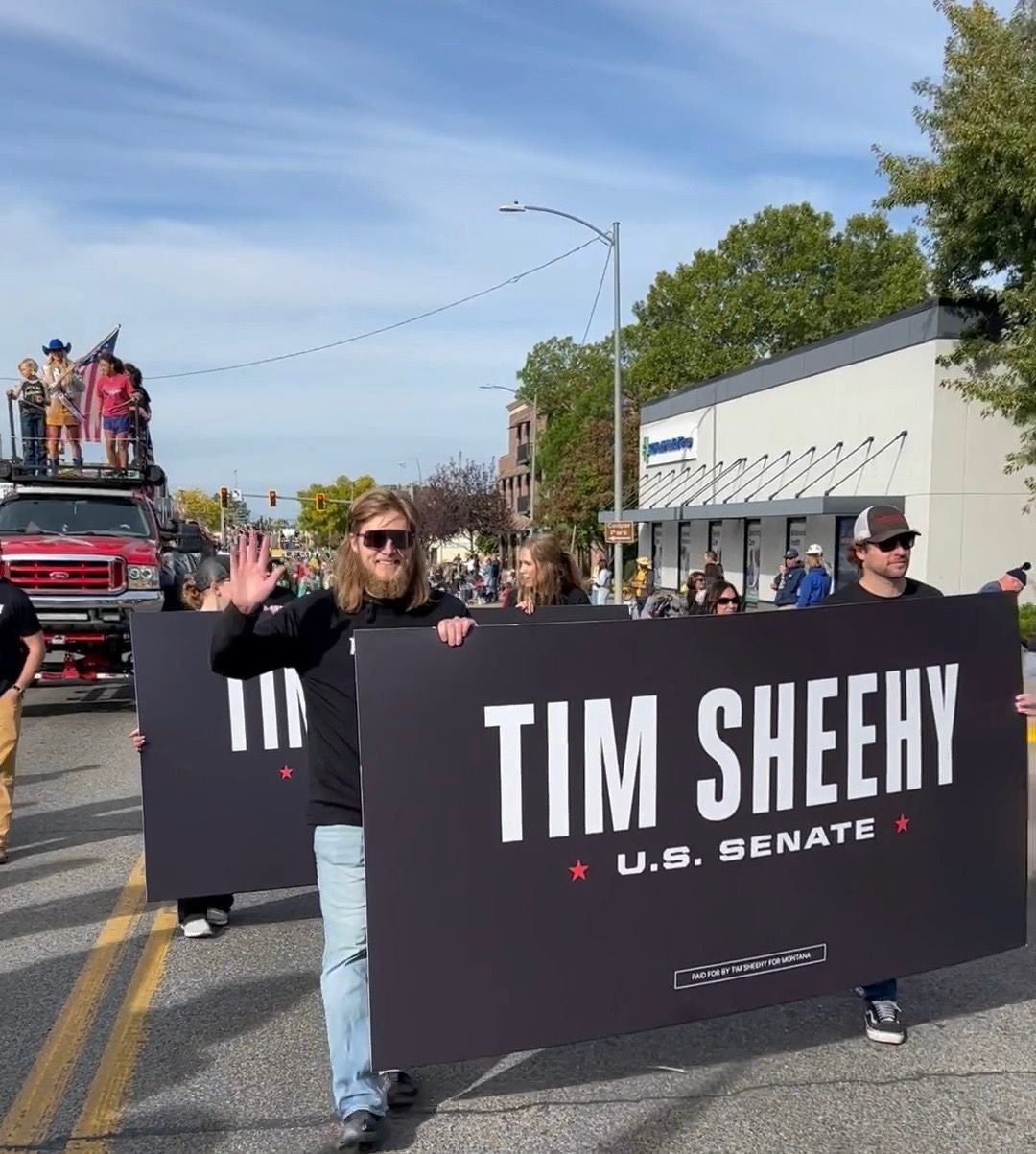 A group of people holding a sign that says tim sheehy