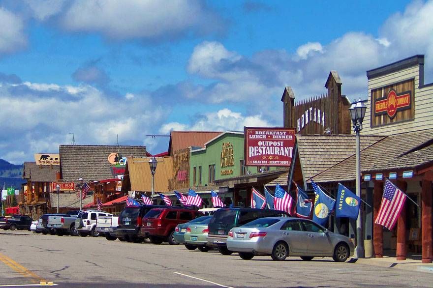 A row of cars are parked in front of a restaurant