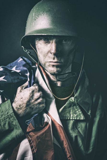 A soldier in a helmet is holding an american flag.