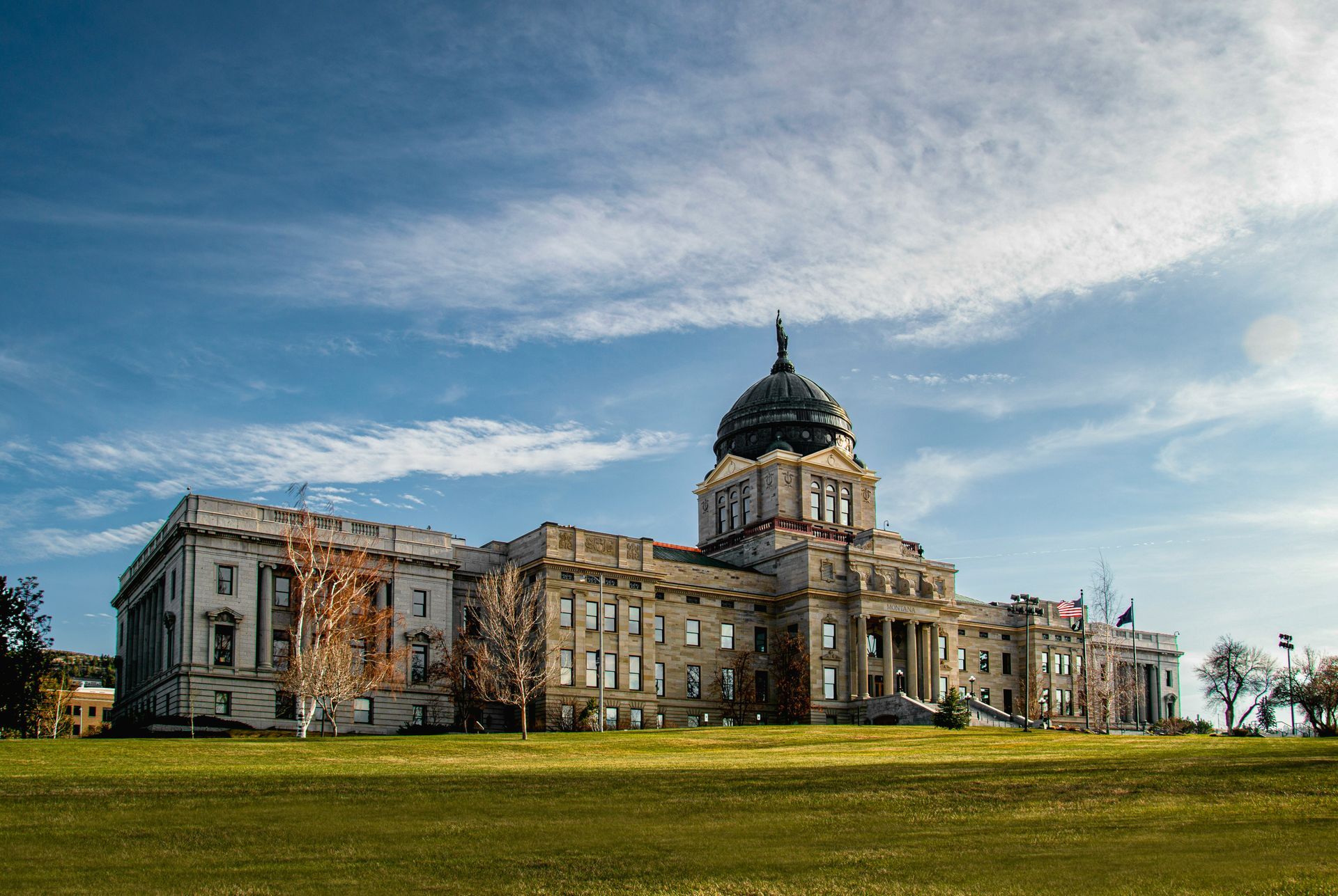 A large building with a dome on top of it is sitting on top of a lush green field.