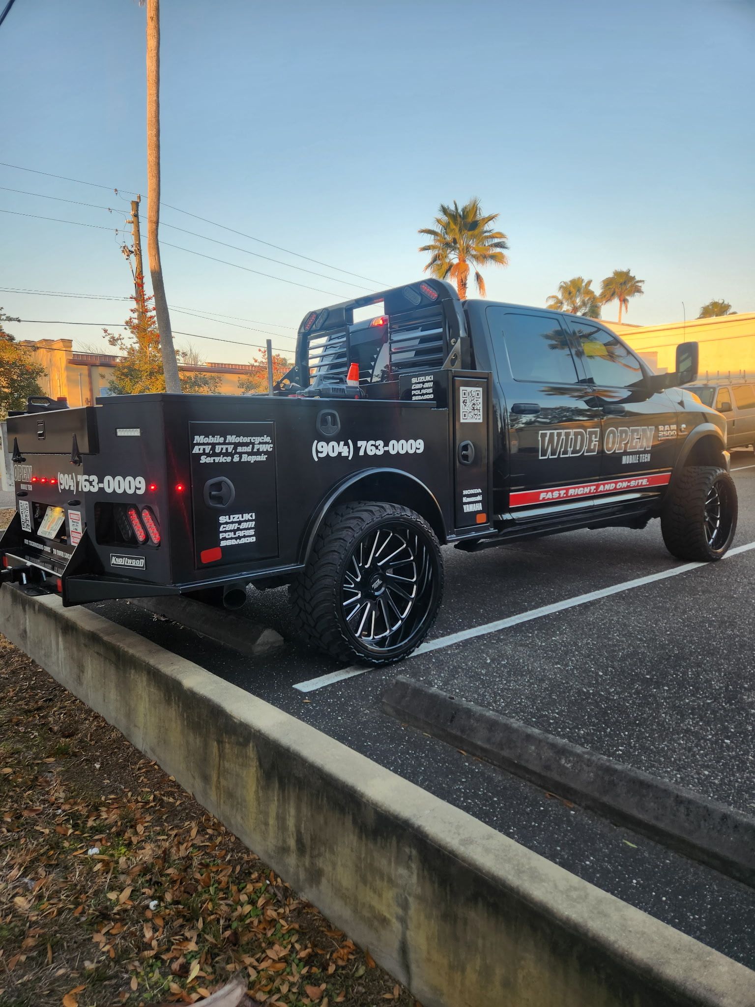Black work truck parked with company logo, wheels, and tools.