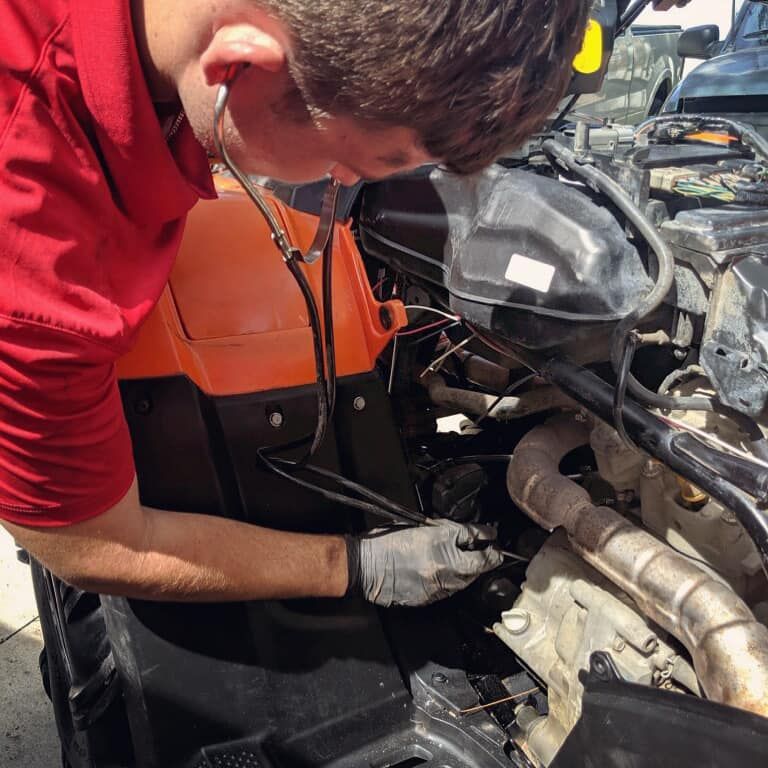 A man in a red shirt is working on a car engine — St. Augustine, FL — Wide Open Mobile Tech