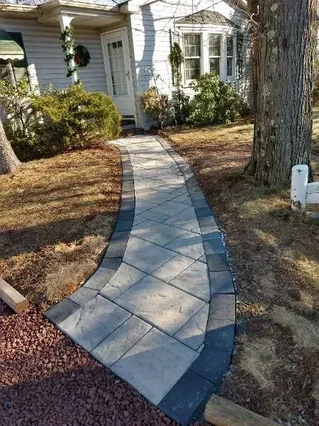 Stone walkway leading to a white house with a curved path and bordering dark gray stones.