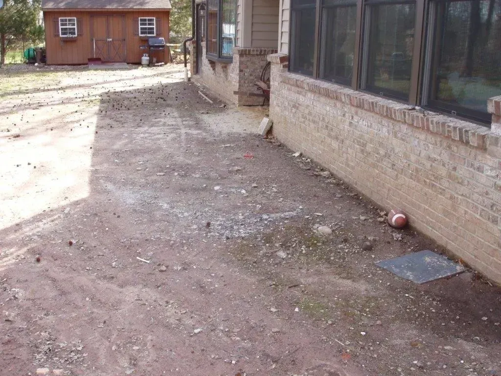 Dirt yard next to a brick building and a small wooden shed.