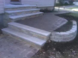 Stone steps and walkway leading to a house. Brickwork with curved retaining wall.