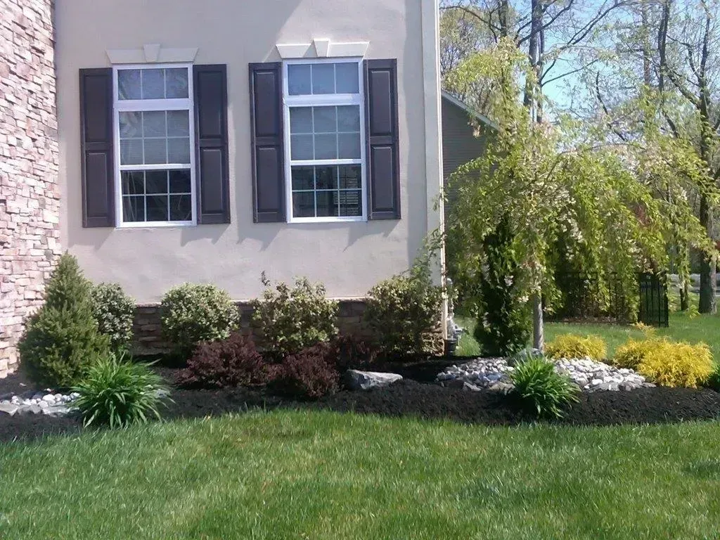 House exterior with landscaping including bushes, mulch, and green lawn.