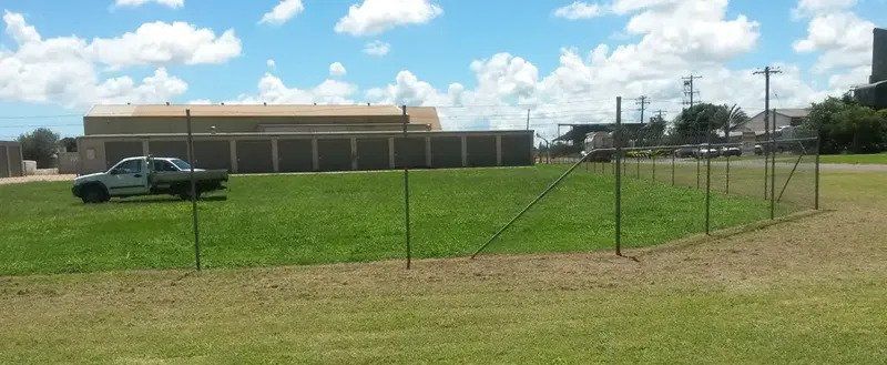 A Truck is Parked in a Grassy Field Behind a Fence — Tableland Self Storage In Atherton, QLD