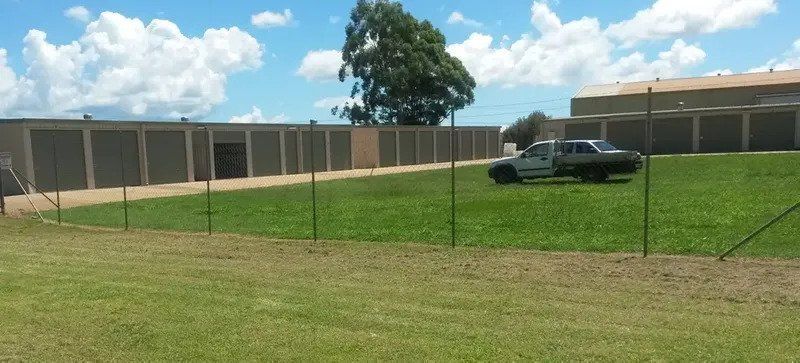A White Truck is Parked in a Grassy Field in Front of a Building — Tableland Self Storage In Atherton, QLD