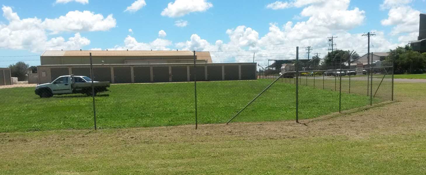 A Truck is Parked in a Grassy Field Behind a Fence — Tableland Self Storage In Atherton, QLD