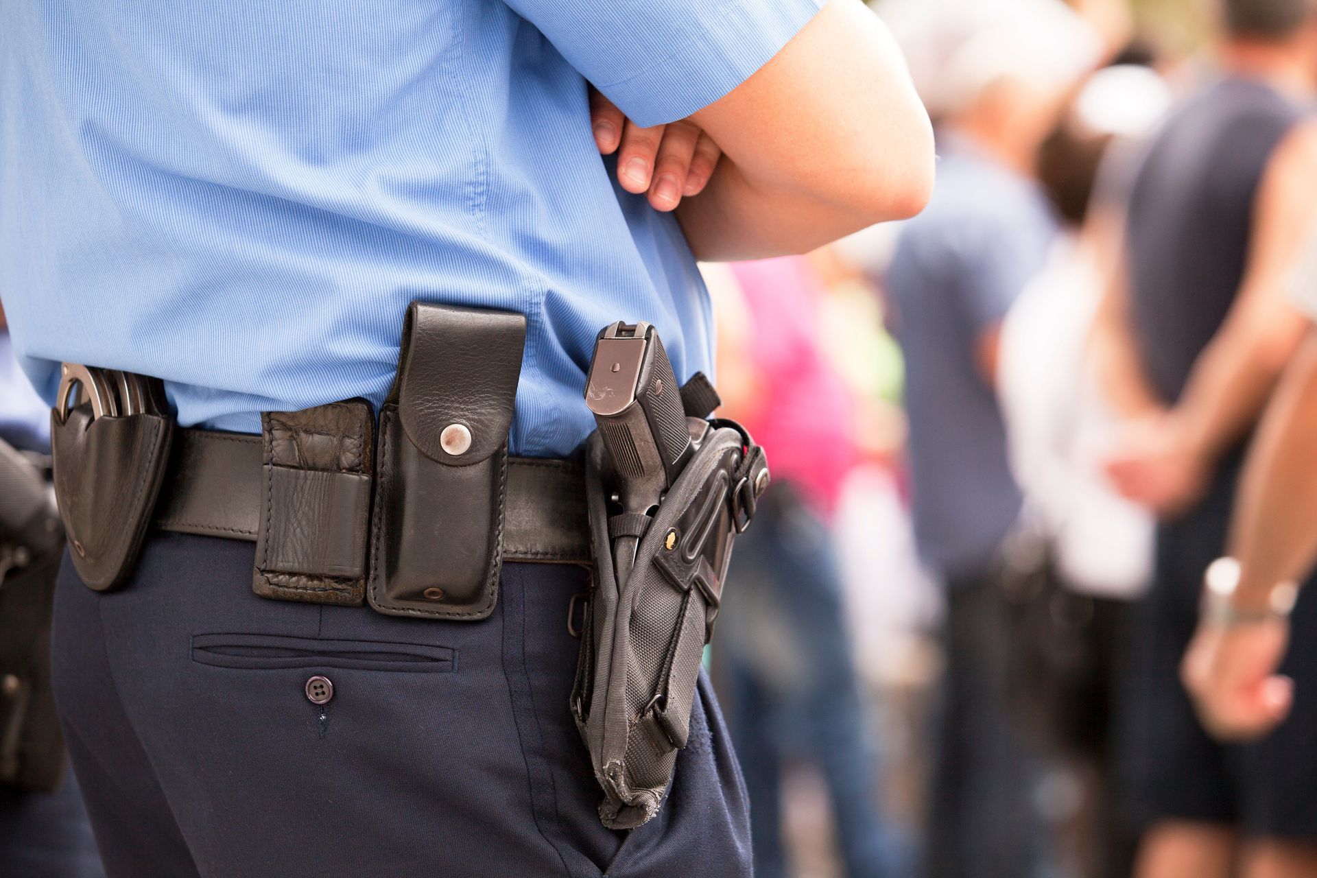 Armed security guard with holstered firearm monitoring a public area.