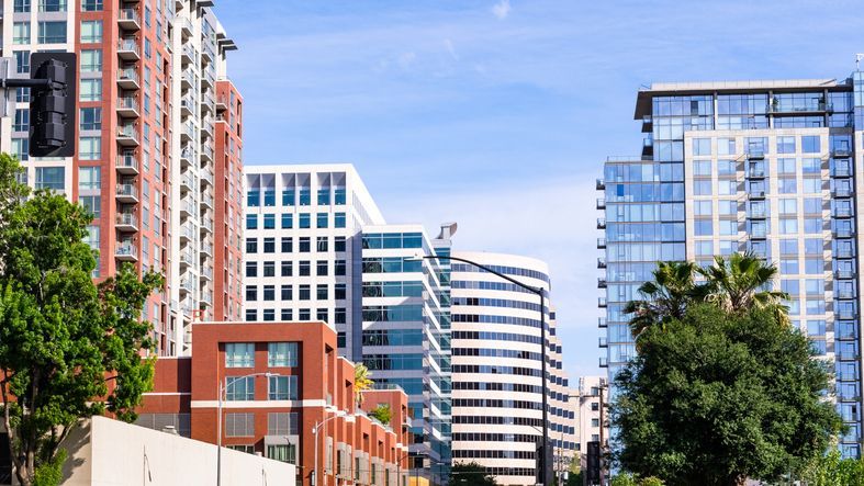 A row of tall buildings in a city with trees in the foreground.
