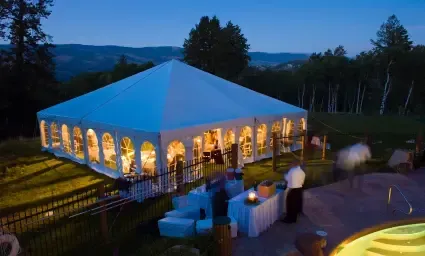 An aerial view of a large white tent filled with people at night.