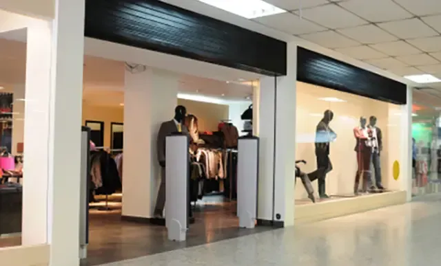 A clothing store in a mall with mannequins in the windows.