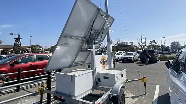 A trailer with a solar panel on top of it is parked in a parking lot.