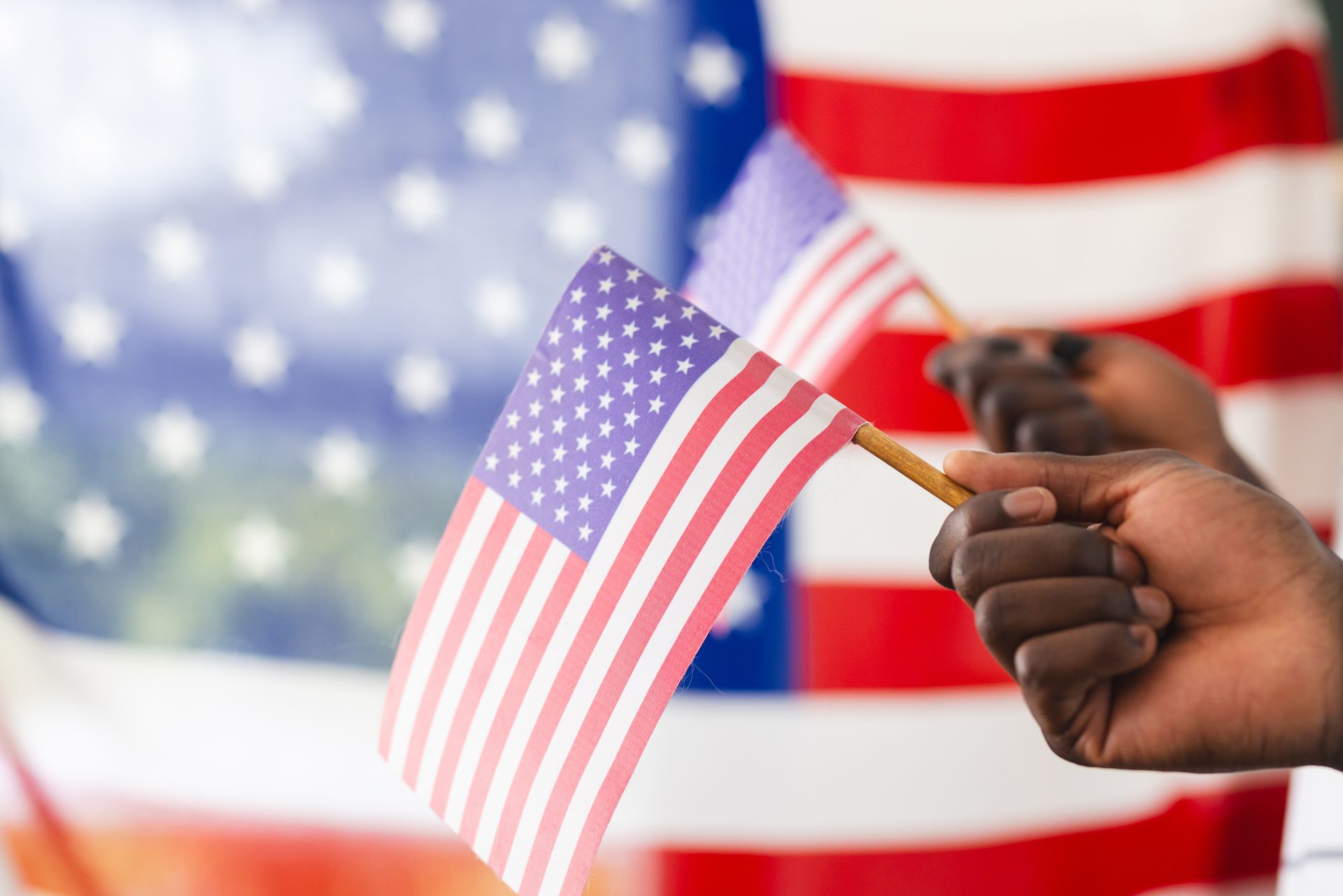 A woman is holding an american flag and a rose at a funeral.